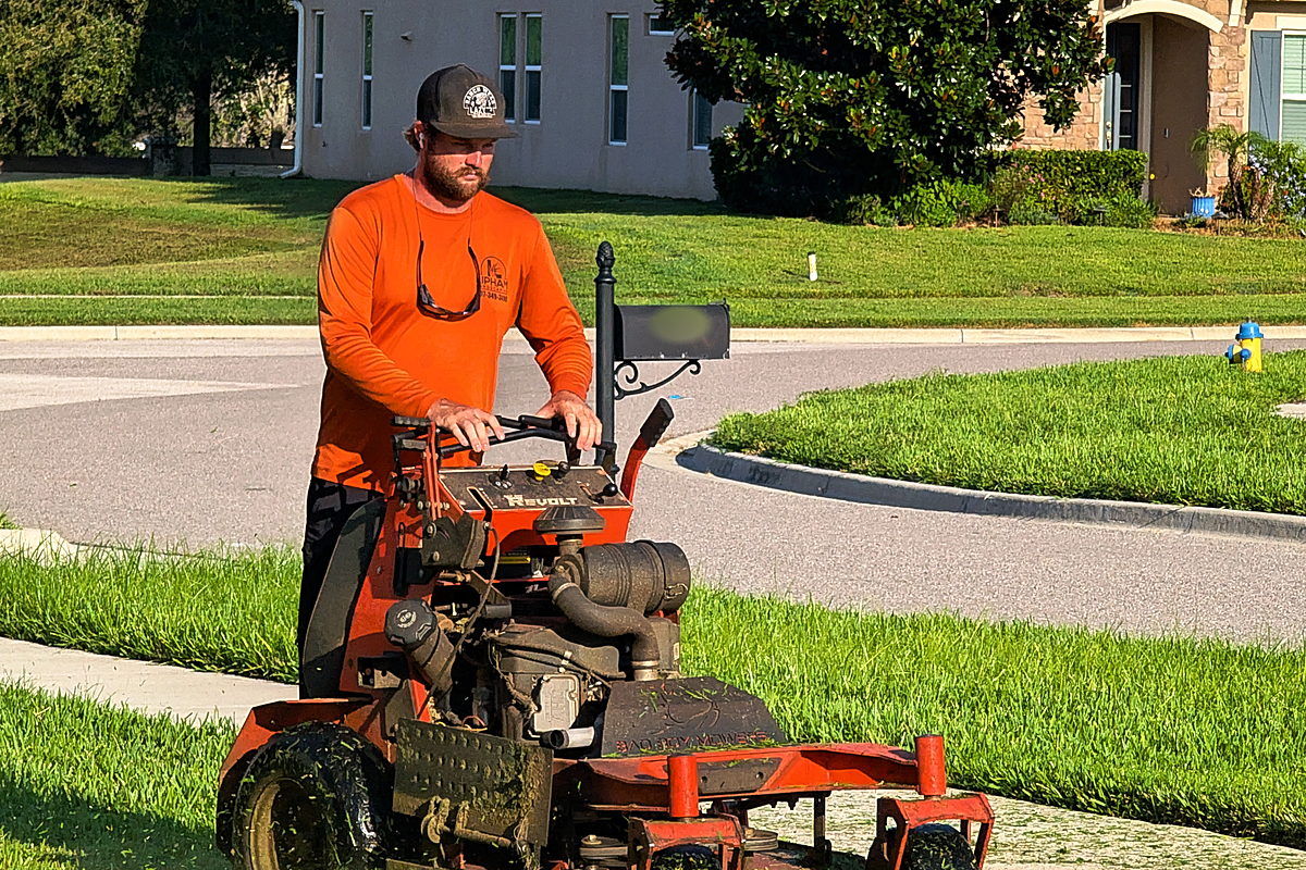 Colton Lipham mowing a front lawn in a South Lake neighbourhood, Lipham Landscaping logo on his shirt