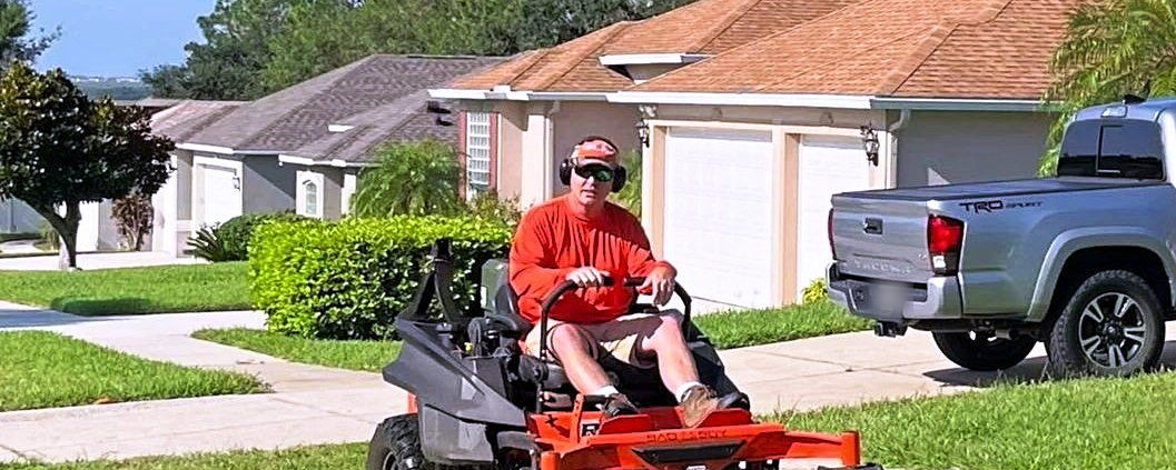 A Lipham Landscaping crew member on a zero-turn mower cutting a front lawn at a Central Florida home
