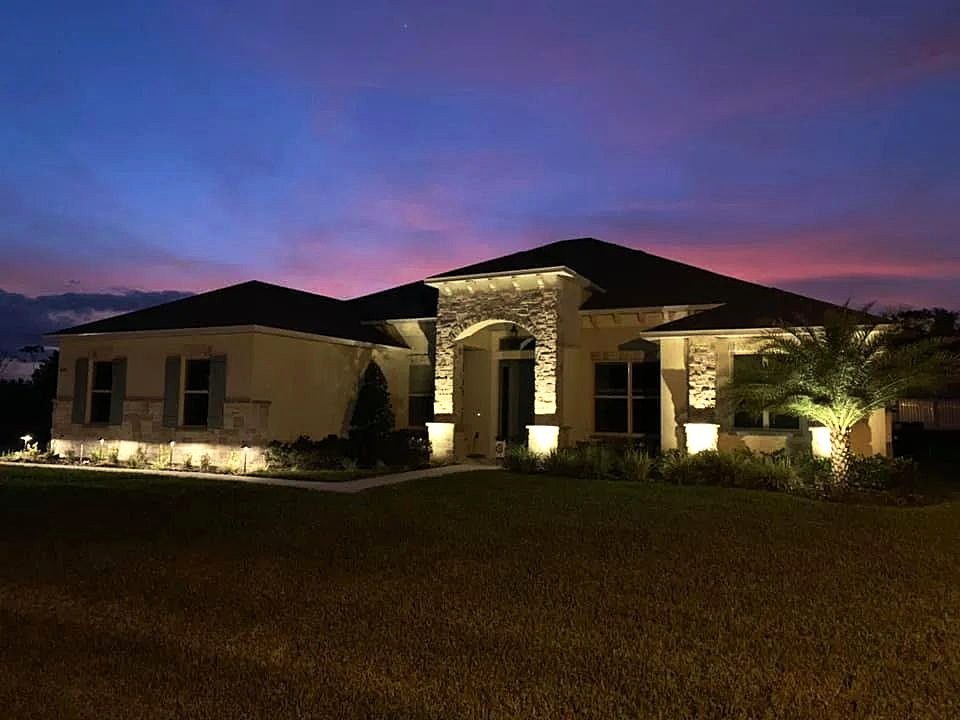 A Central Florida home at dusk with landscape and architectural lighting installed by Lipham Landscaping