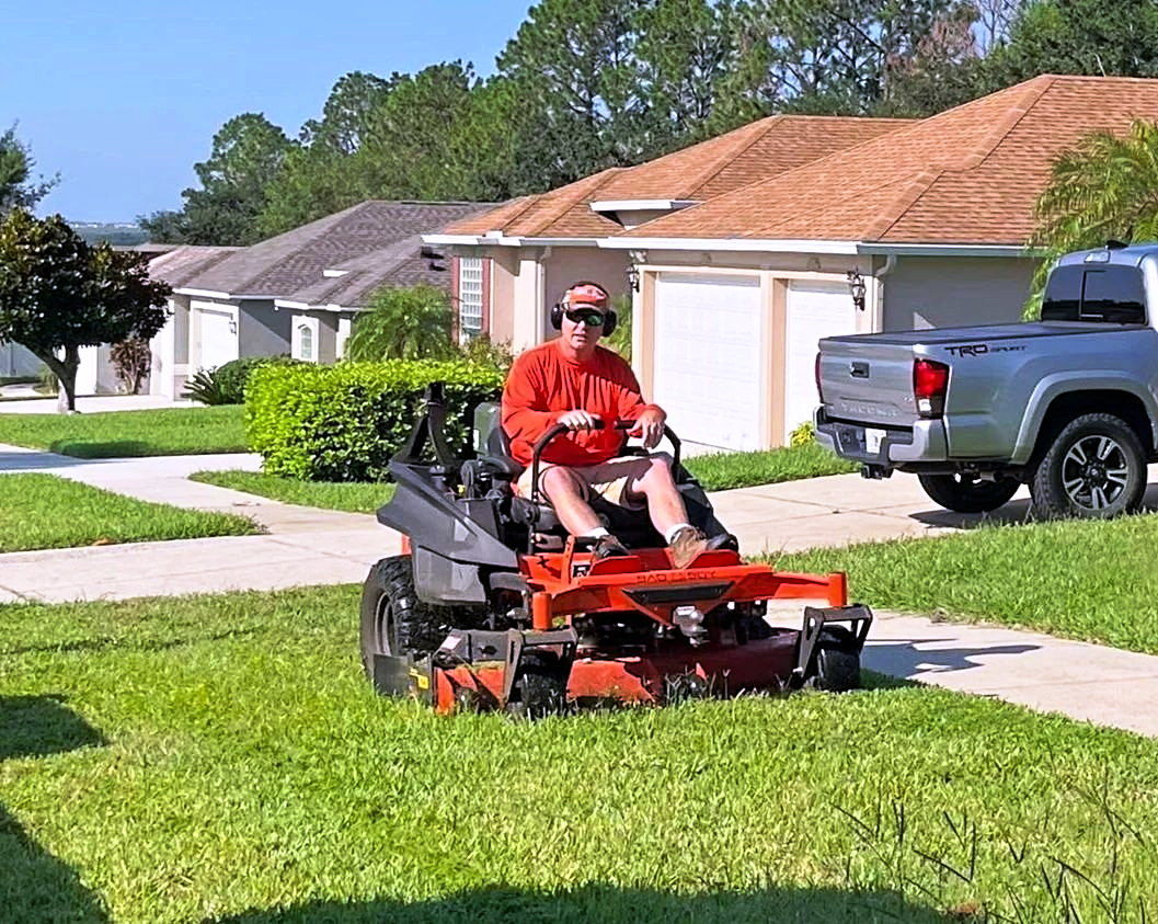 A Lipham Landscaping crew member mowing a front lawn at a Montverde home